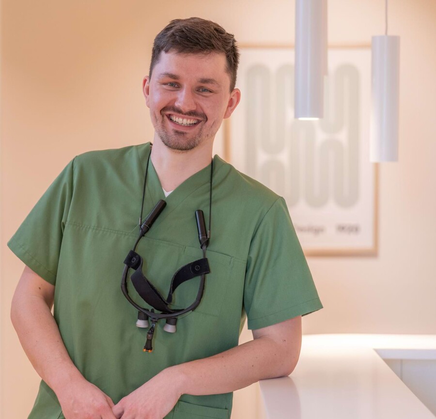 Fotoaufnahme: Christopher Schwenn lehnt am Empfang und lächelt in die Kamera