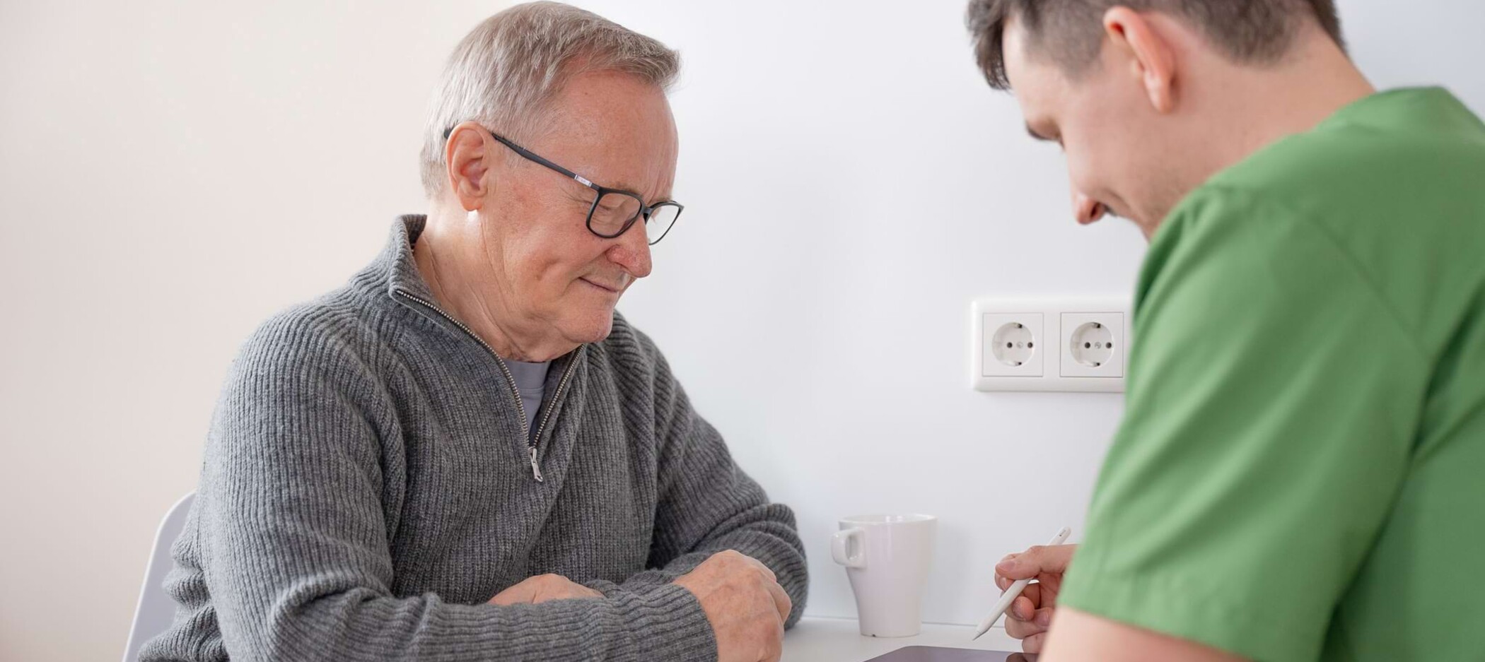 Fotoaufnahme: Patient und Chrisopher Schwenn besprechen sich am Tisch
