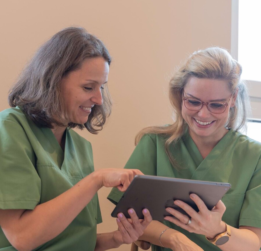 Fotoaufnahme: Zwei Mitarbeiterinnen arbeiten gemeinsam am Tablet
