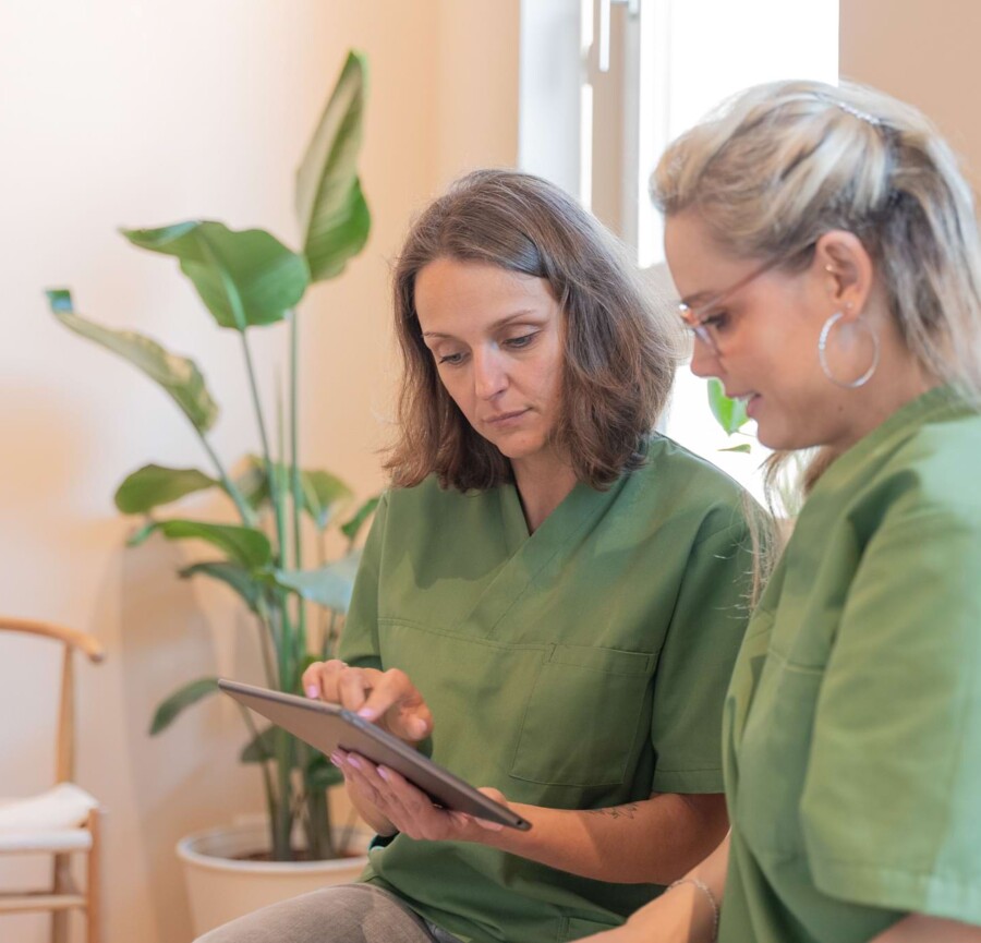 Fotoaufnahme: Zwei Teamkolleginnen schauen auf ein Tablet