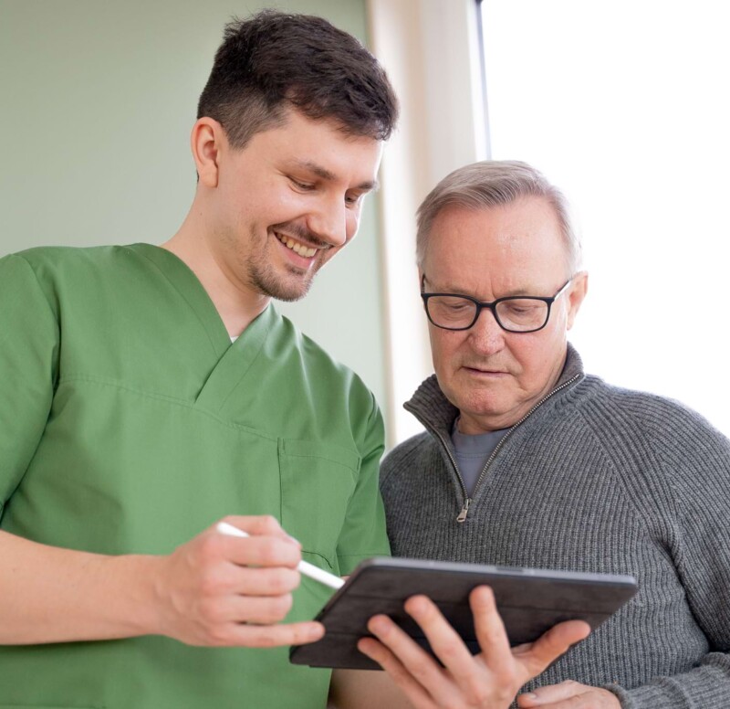 Fotoaufnahme: Dr. Schwenn zeigt einem Patienten etwas am Tablet